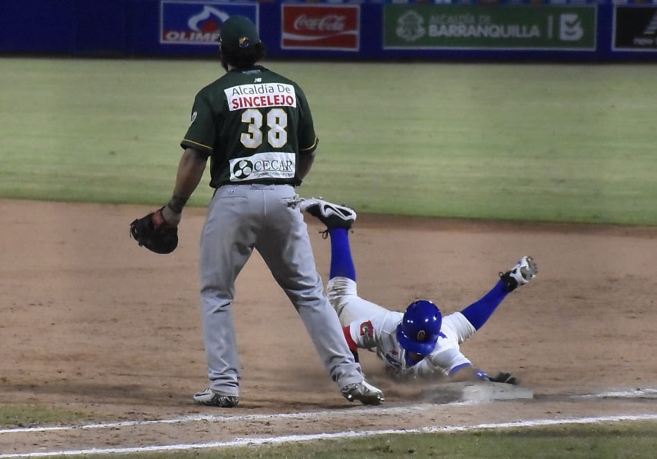 Charlie Mirabal se desliza en primera ante la mirada de Jorge Alfaro.