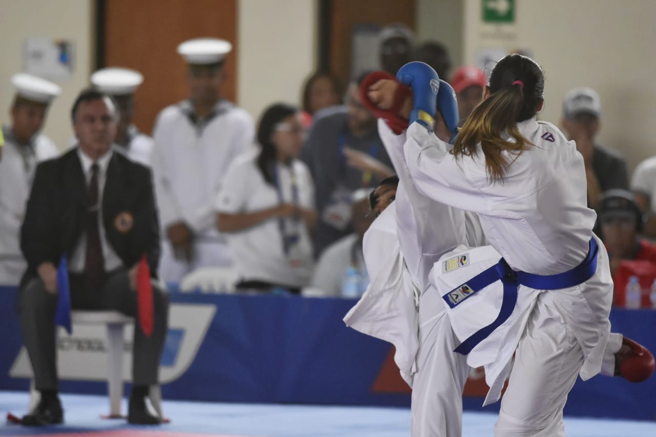 Claudymar parando con su mano una patada de parte de Karina Díaz.