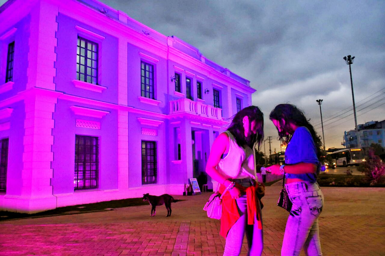 Transeúntes disfrutan de la vista de la Intendencia Fluvial iluminada.
