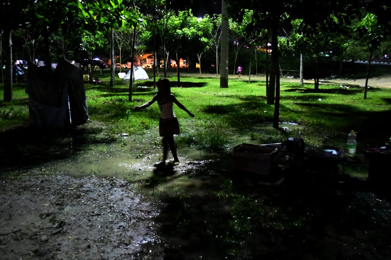 Los niños juegan con la arena y el agua en medio de la precaria situación.