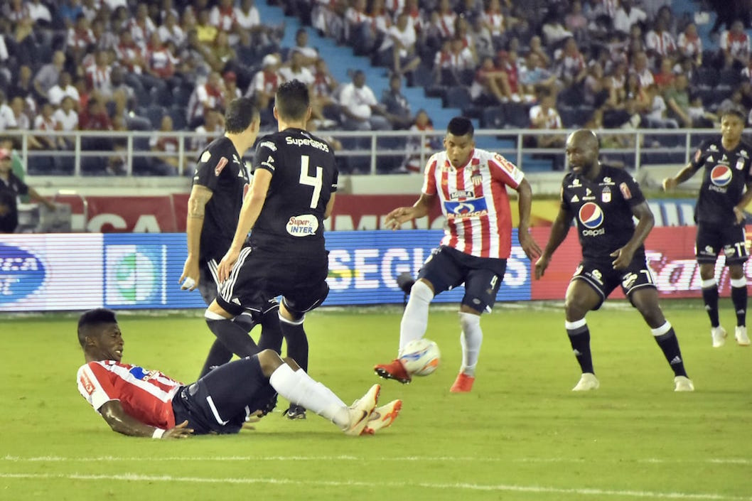 David Murillo intenta ingresal a la zona americana mientras Yony González permanece en el piso.