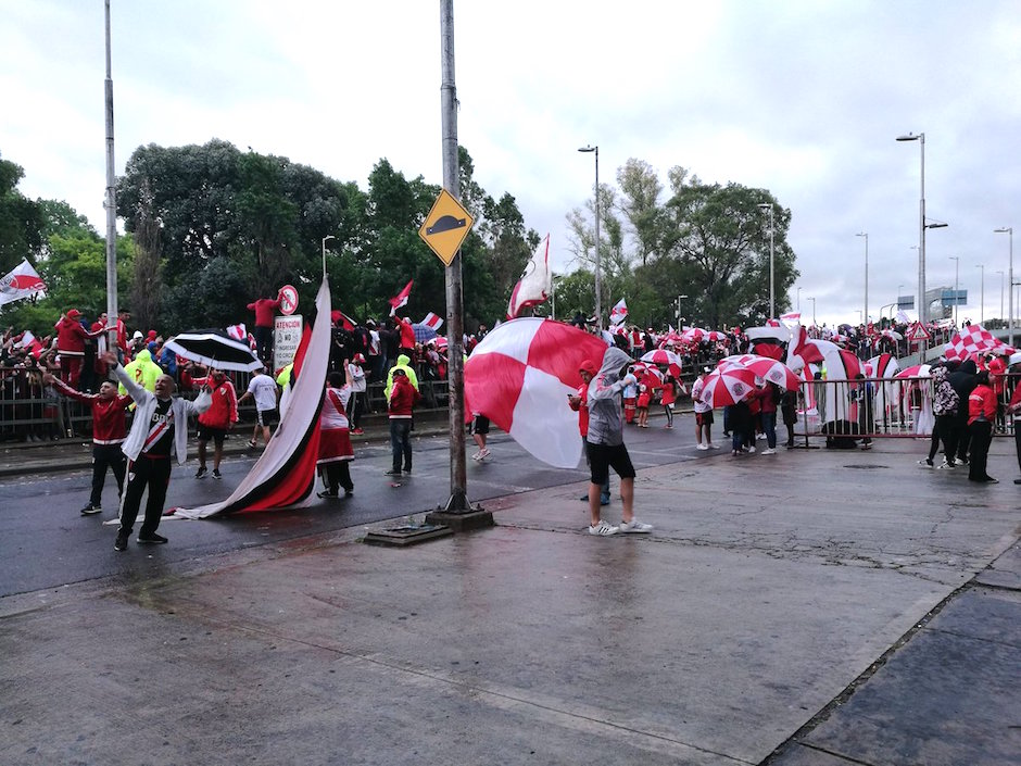 Aficionados protegiéndose con paraguas.