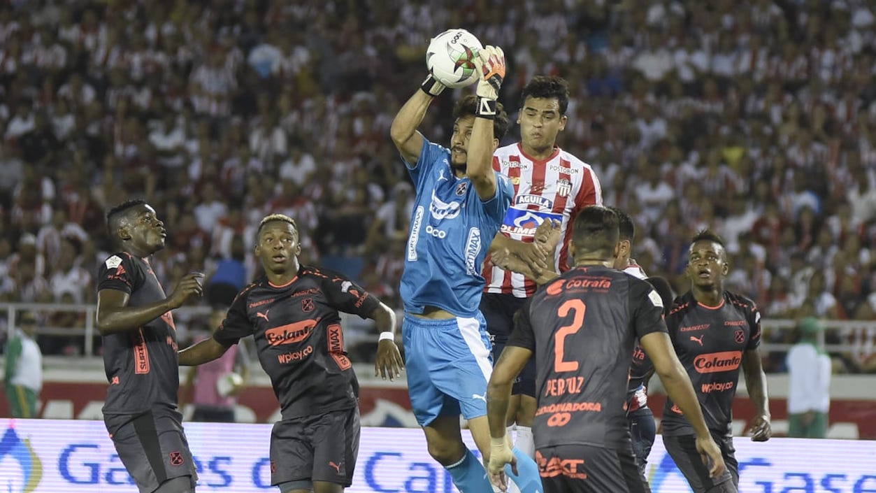 El arquero David González controla el balón, ante la llegada de Jefferson Gómez.