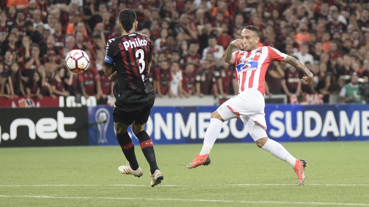 Jarlan Barrera rematando ante la marca de Lucho González.