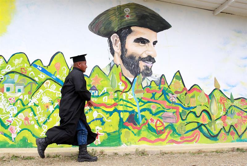 Un estudiante corre frente a un mural con la imagen de un comandante de las FARC, durante la ceremonia de graduación en Caldono, Cauca (Colombia)