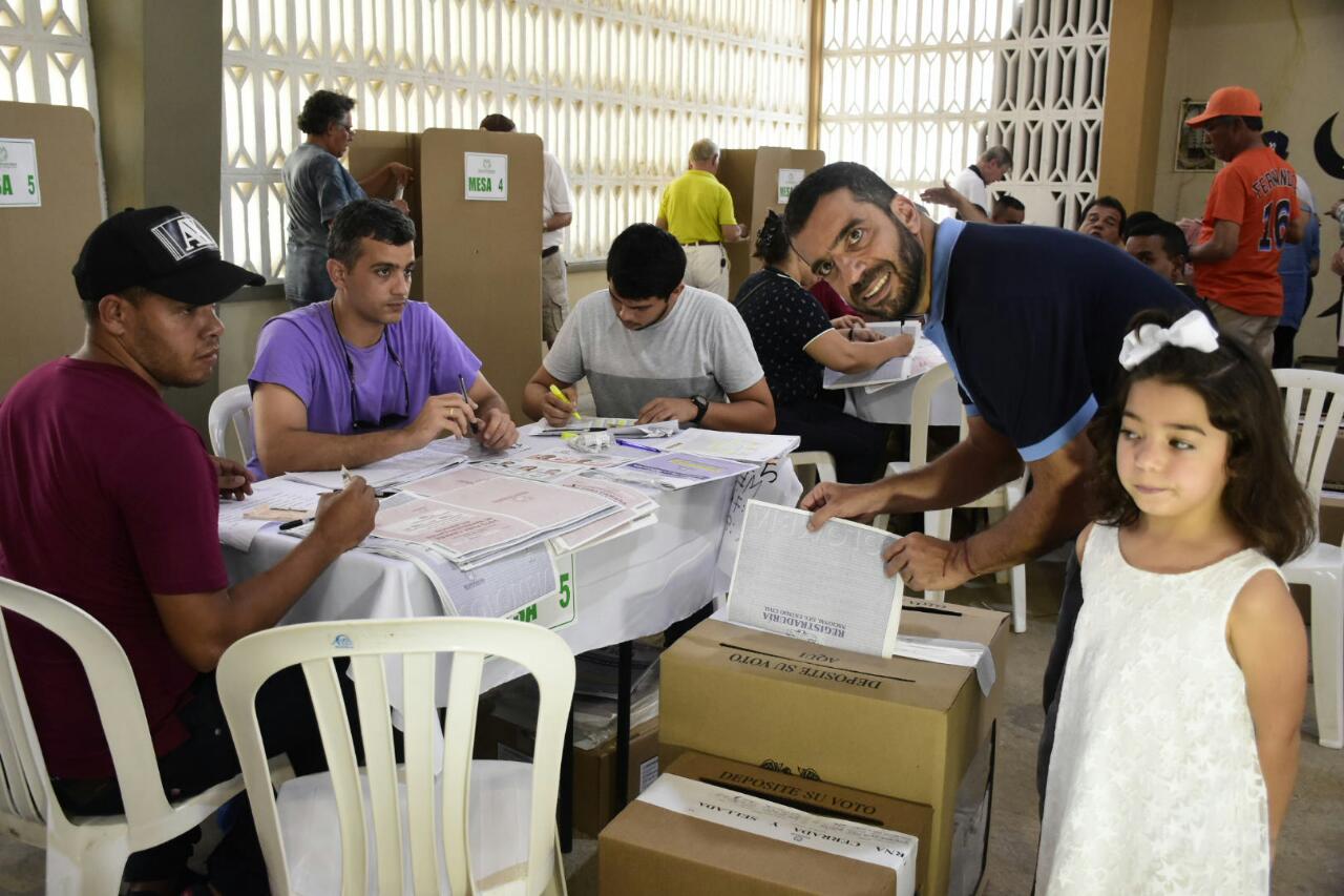 Arturo Char, acompañado de su pequeña hija, deposita su voto.