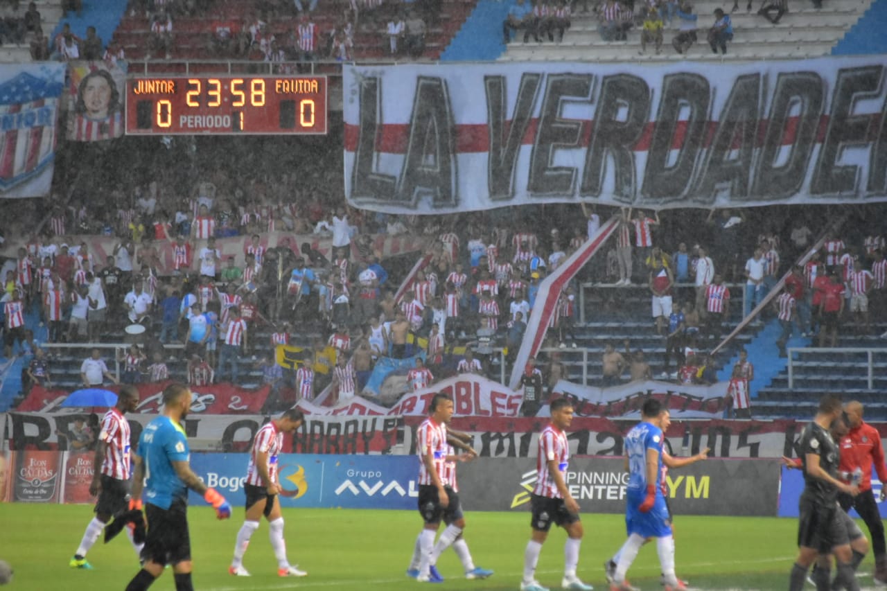 Los equipos abandonando la cancha tras la suspensión del partido por lluvia y tormenta.