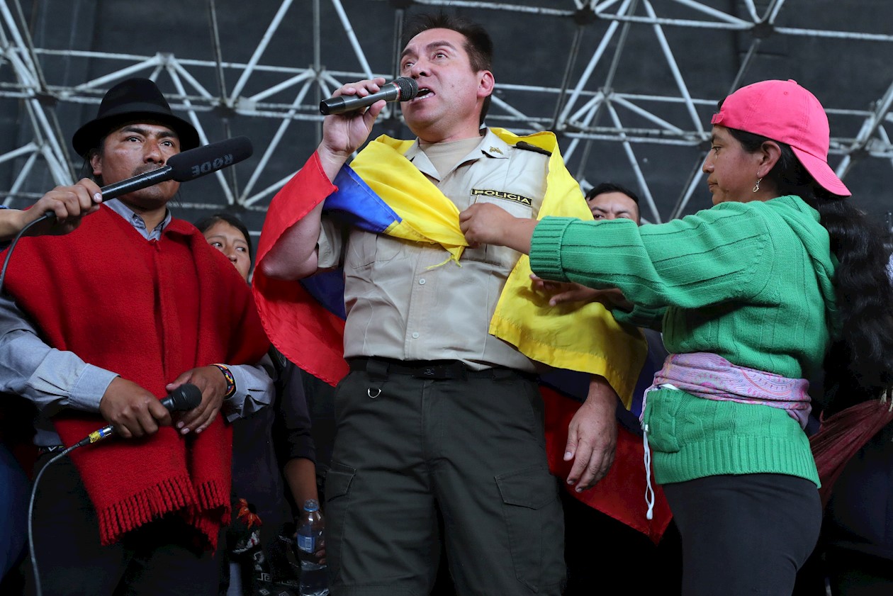 EFE Uno de los policías retenidos (c) habla junto a una joven indígena (d) que le coloca una bandera nacional sobre sus hombros este jueves en la Casa de la Cultura de Quito (Ecuador).