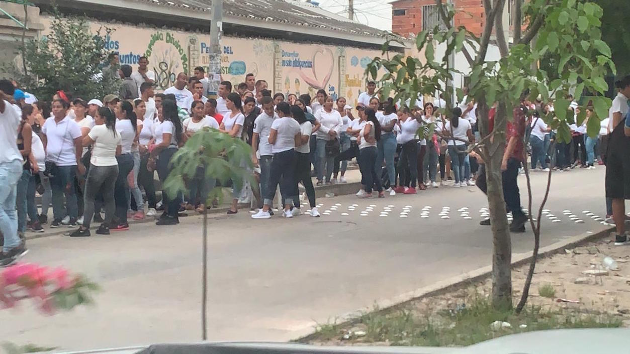 Personas con camisetas blancas disponiéndose a votar.