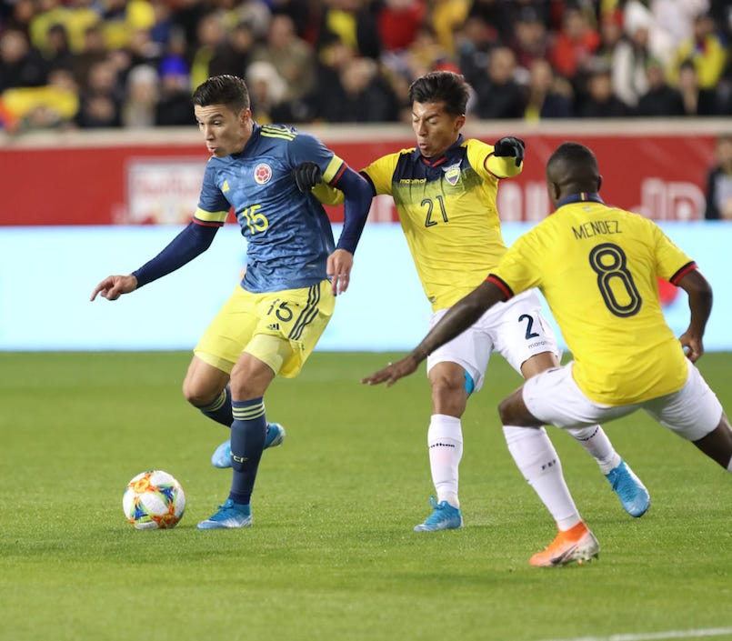 Mateus Uribe controlando el balón entre Alan Franco y Jhegson Méndez.