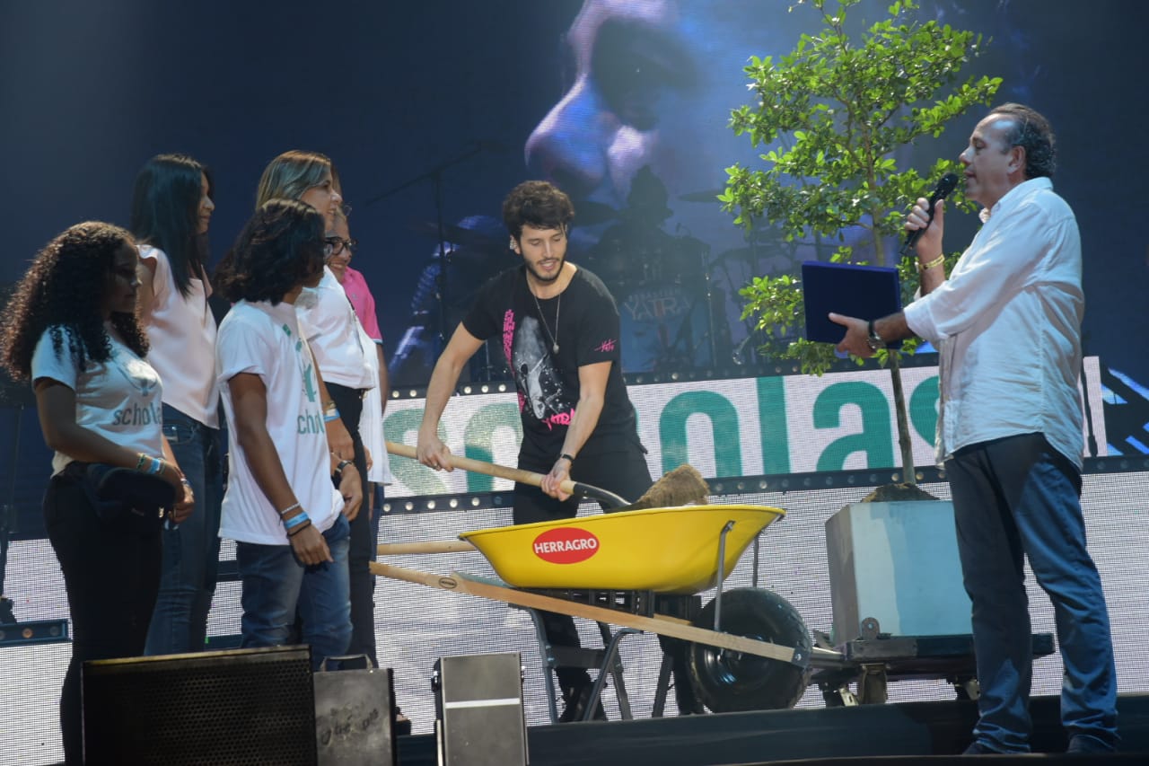 Yatra plantando un olivo con voluntarios de scholas, previo a interpretar la canción 'En guerra'.