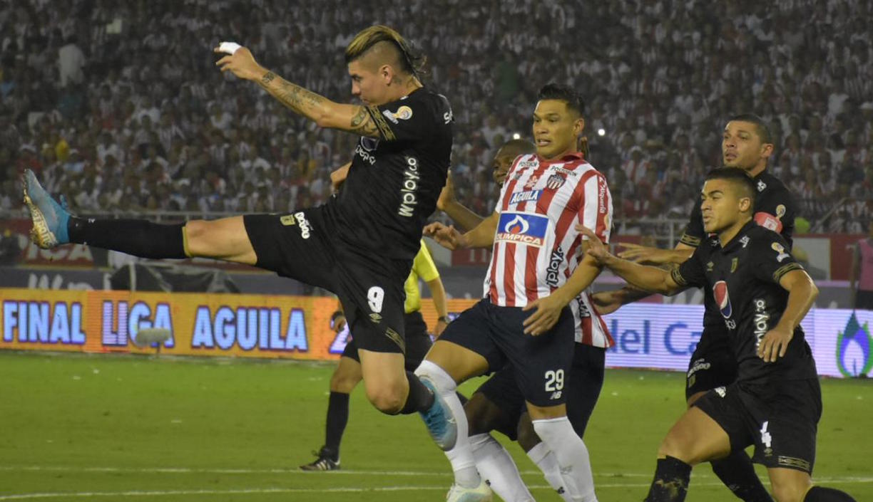 Michael Rangel rechazando el balón ante la entrada de Teófilo Gutiérrez.