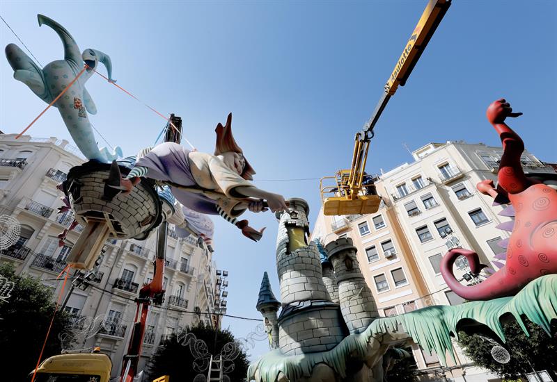 Operarios falleros trabajan con grandes grúas para ensamblar las piezas mas grandes y altas de las distintas fallas.