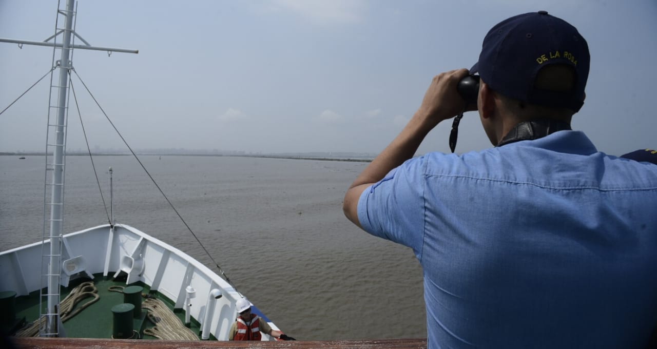Un miembro de la tripulación mira por los binoculares la entrada a Bocas de Ceniza.