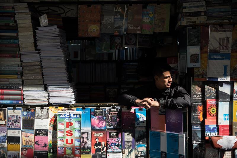 Un hombre atiende una venta de libros este martes, durante el Día Internacional del Libro en la calle San Diego, en el centro de Santiago (Chile). Desde los años 70 este rincón de la capital chilena se ha convertido en un lugar de referencia para los lectores, gracias a la concentración de librerías y quioscos especializados.