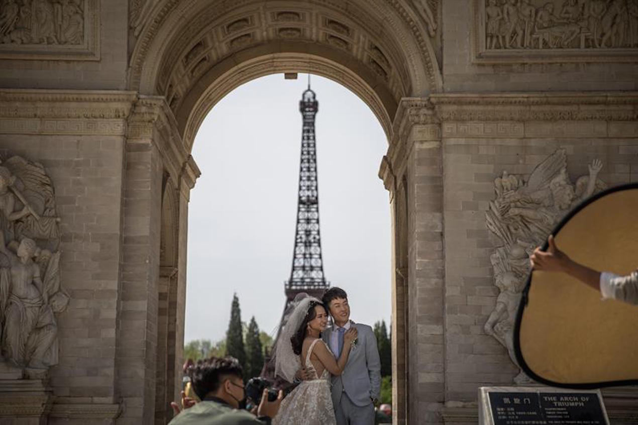 Una pareja china posa para sus fotos preboda frente a una réplica de la Torre Eiffel, en el World Park, en Pekín (China).