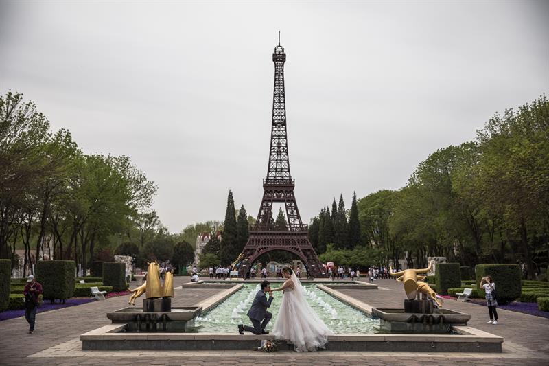 Una pareja china posa para sus fotos preboda frente a una réplica de la Torre Eiffel, en el World Park.