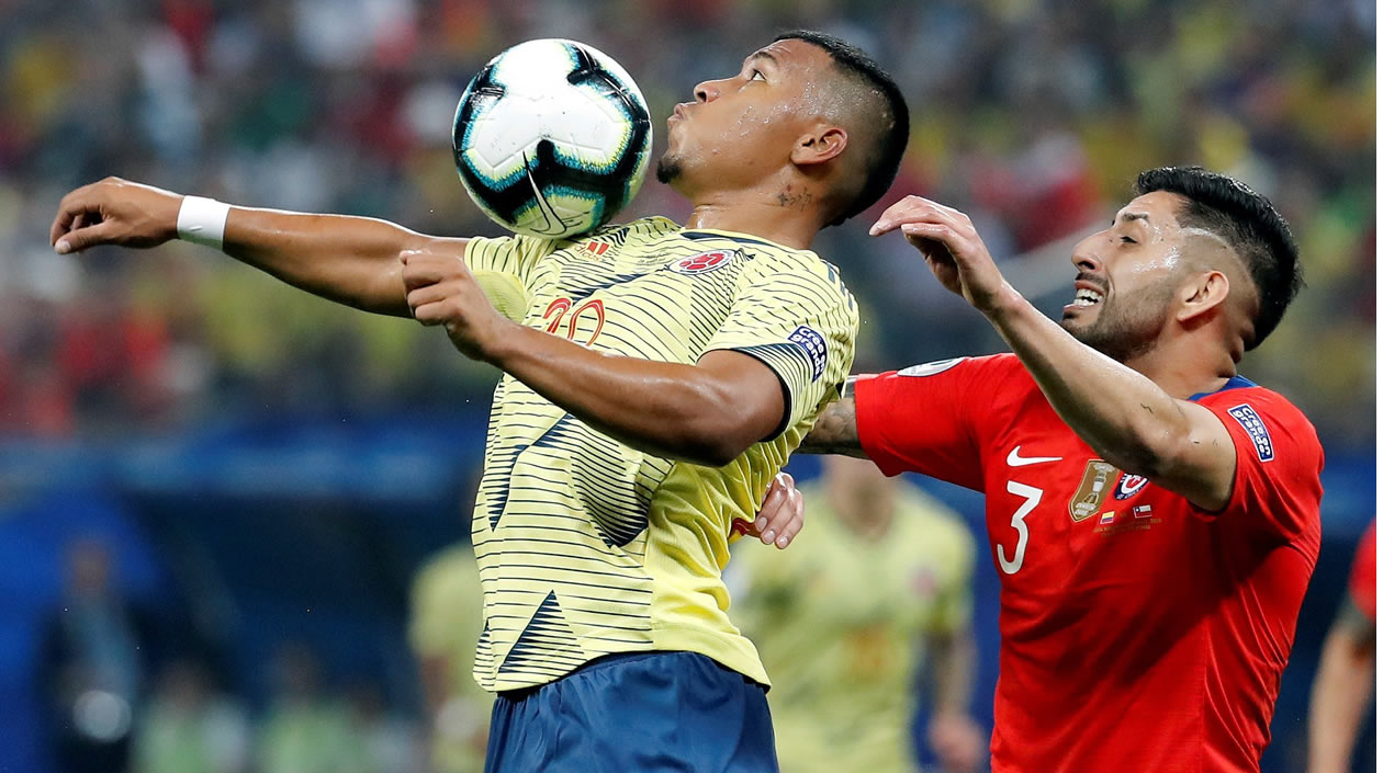 Roger Martínez disputa el balón con Guillermo Maripan de Chile.