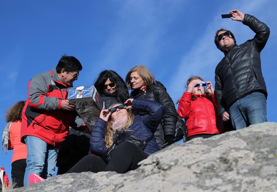 Espectadores observan el sol con diferentes objetos durante el eclipse solar total, este martes en la ciudad de Merlo, San Luis (Argentina). 