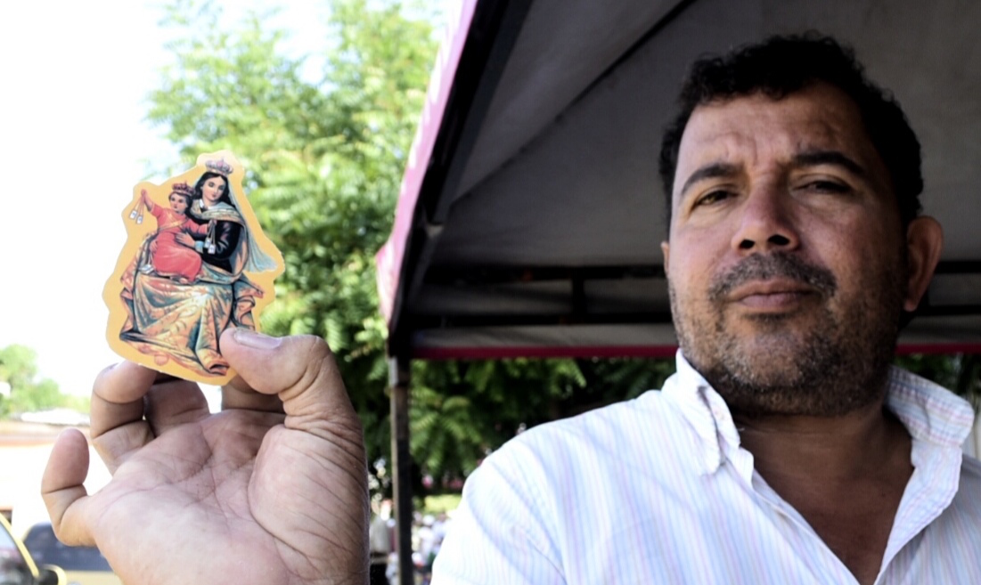 Un feligrés mostrando una estampa de la Virgen.