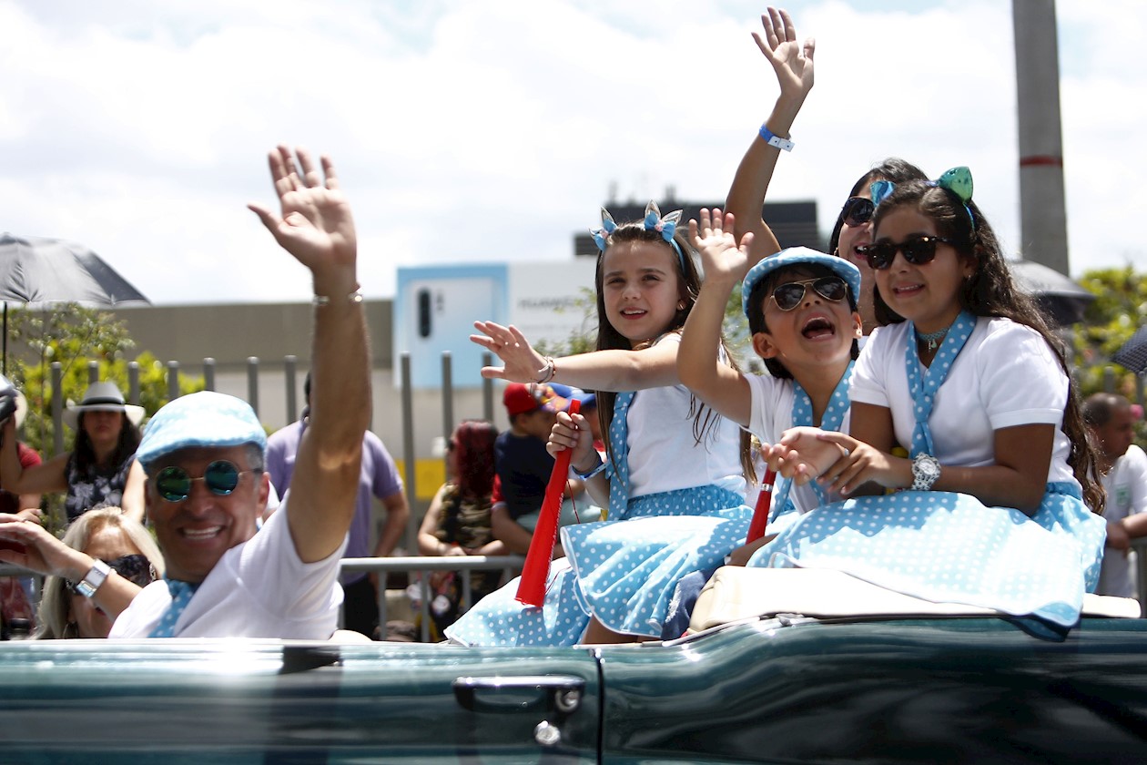 Familia participante del desfile saluda a los asistentes del evento.