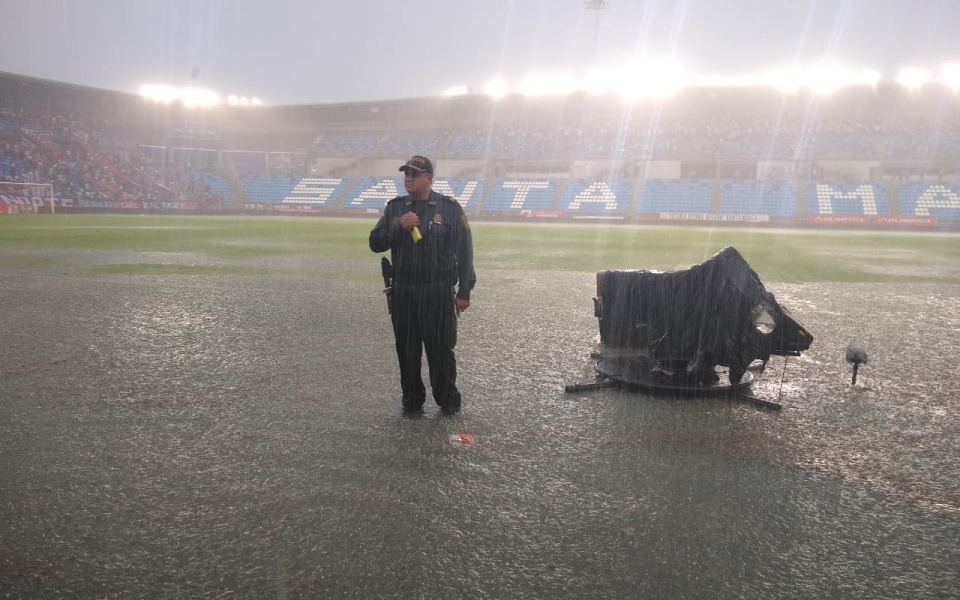 Un policía observa en medio de la tormenta y las cámaras de la transmisión se protegen.