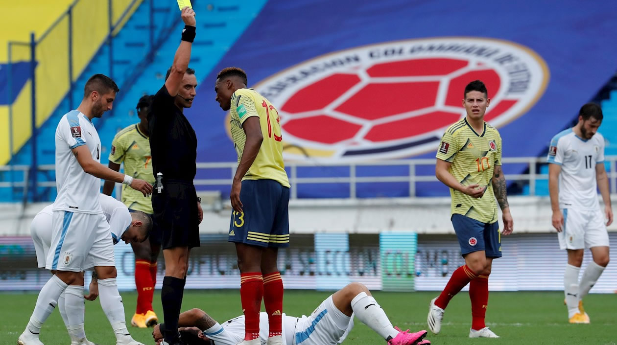 El árbitro Fernando Rapallini sanciona con tarjeta amarilla a Yerry Mina