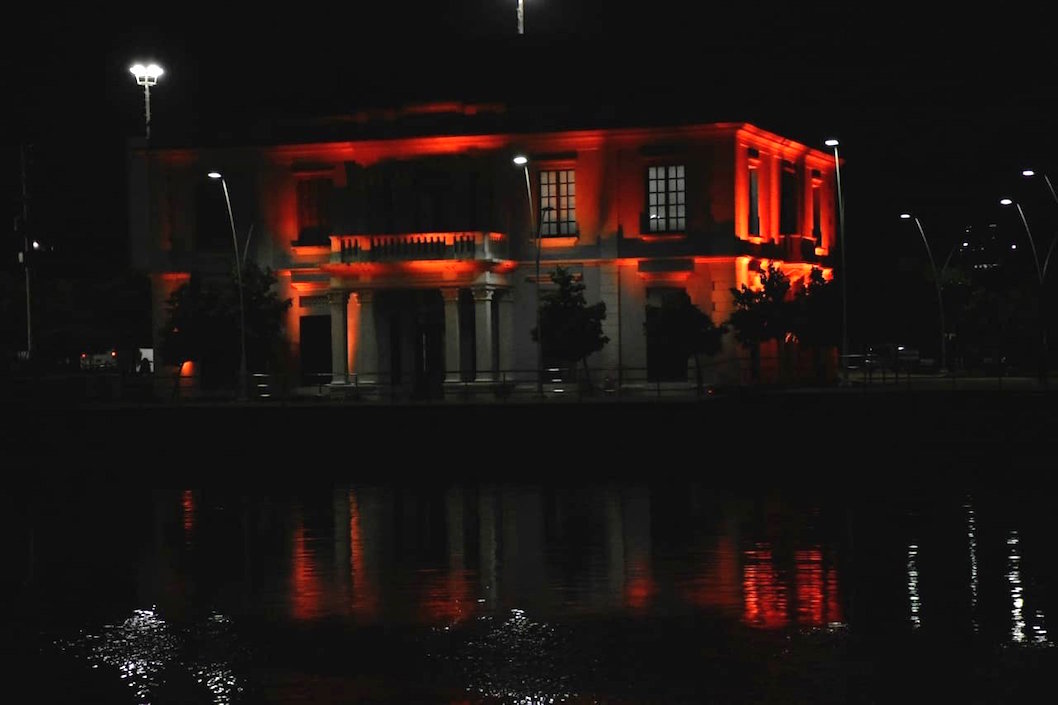 La antigua Intendencia Fluvial iluminada de naranja.