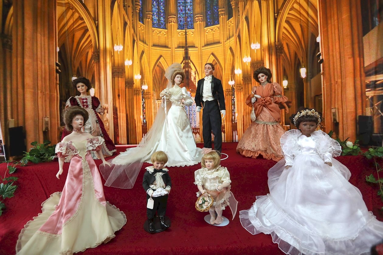 Uno de los segmentos destacados es la instalación "Boda de Muñecas", que incluye 13 piezas de porcelana de la década de 1920 colocadas en una tarima cubierta con una tela roja y decorada con flores, con la emblemática Catedral de San Patricio en Nueva York como fondo.