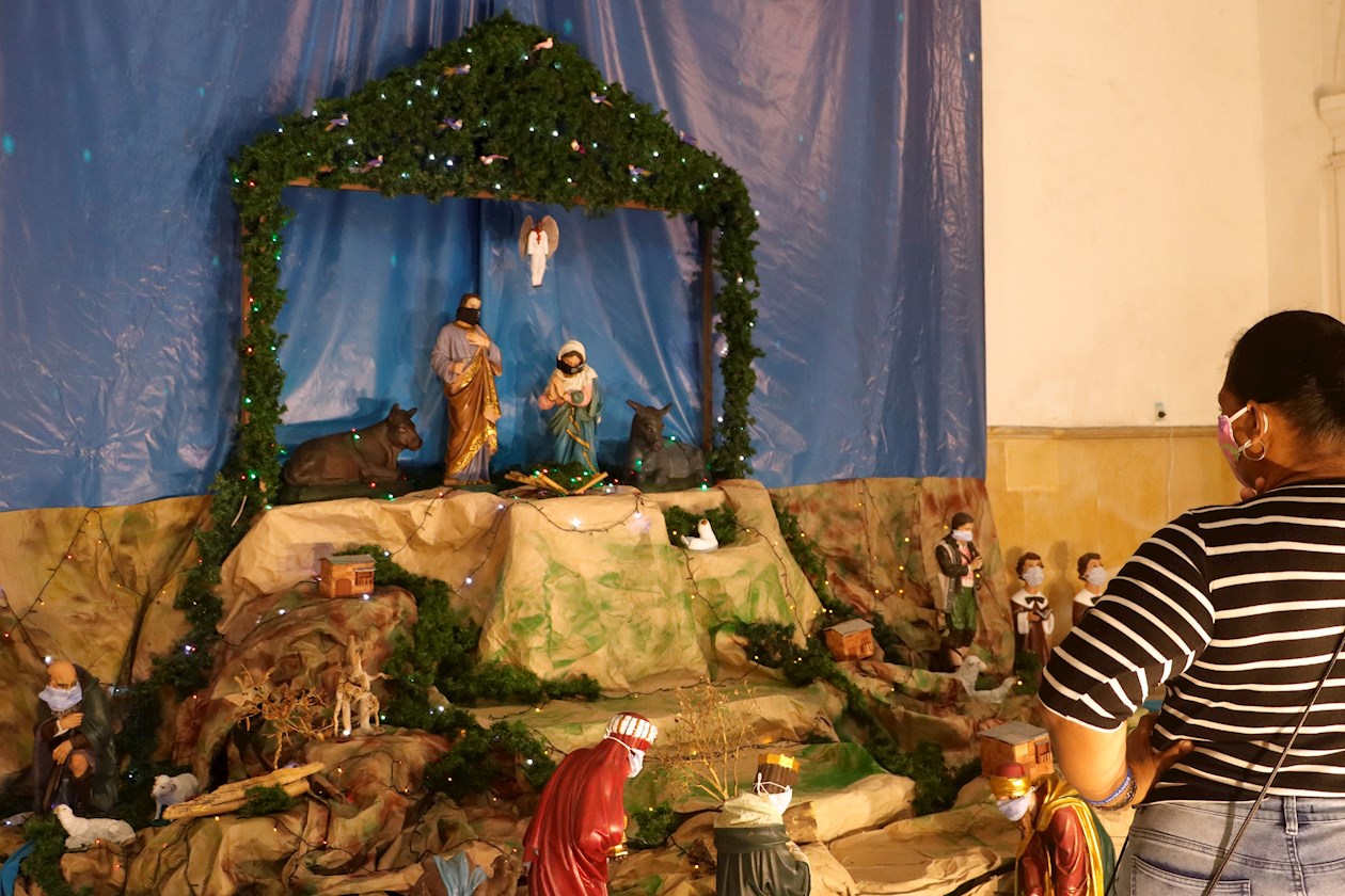 Una mujer observa un pesebre cuyas figuras tienen tapabocas.