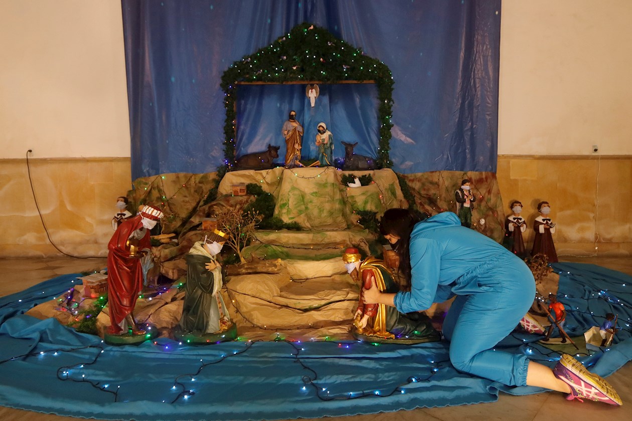 Una mujer acomoda la figura de un rey mago que adorna un pesebre.