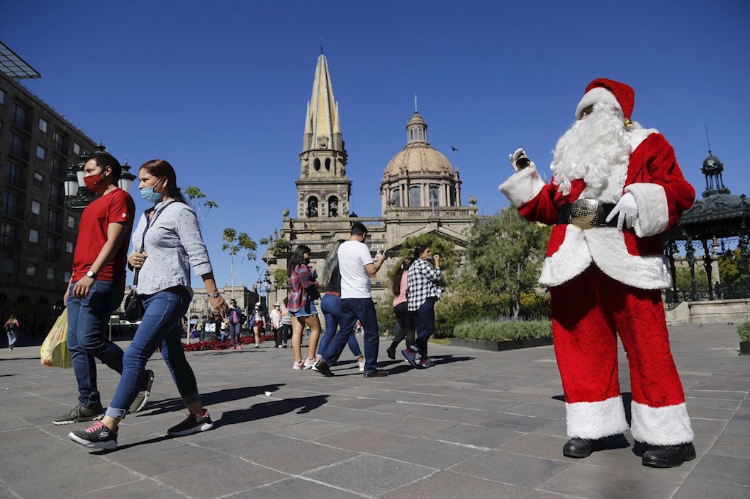 Una persona vestida de Papa Noel saludando a los ciudadanos en el Cemtro Histórico de Guadalajara (México).