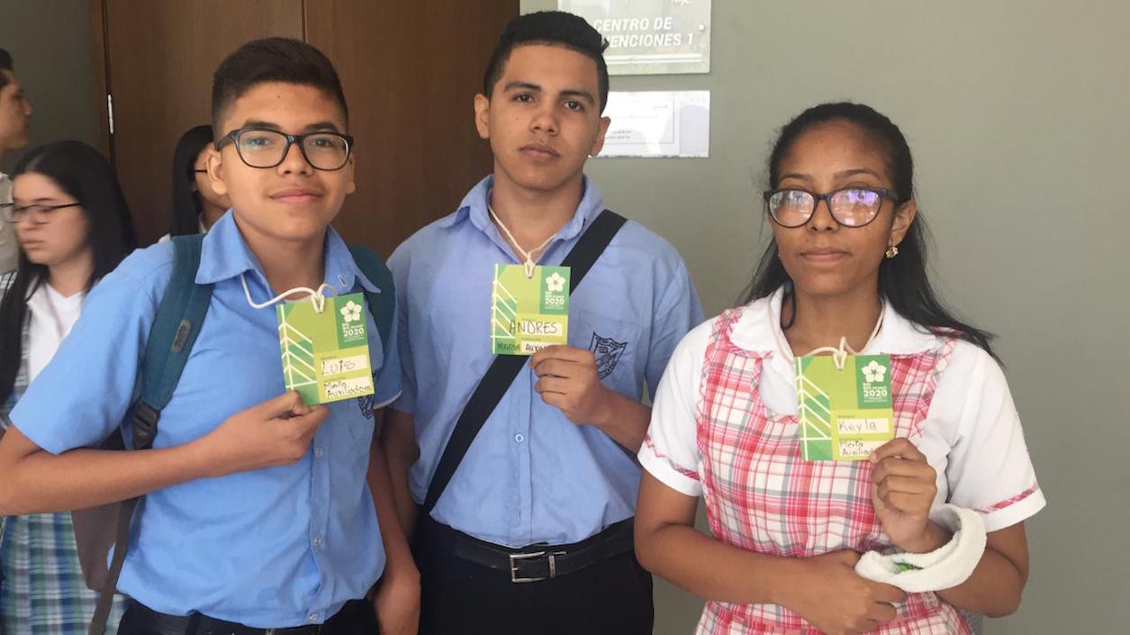 Estudiantes muestran las credenciales elaboradas con papel reciclado.