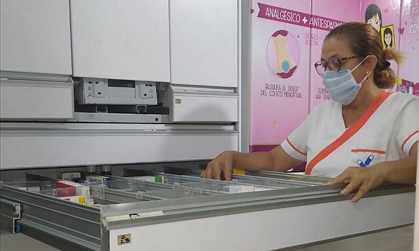 Empleada de una farmacia atendiendo clientes.