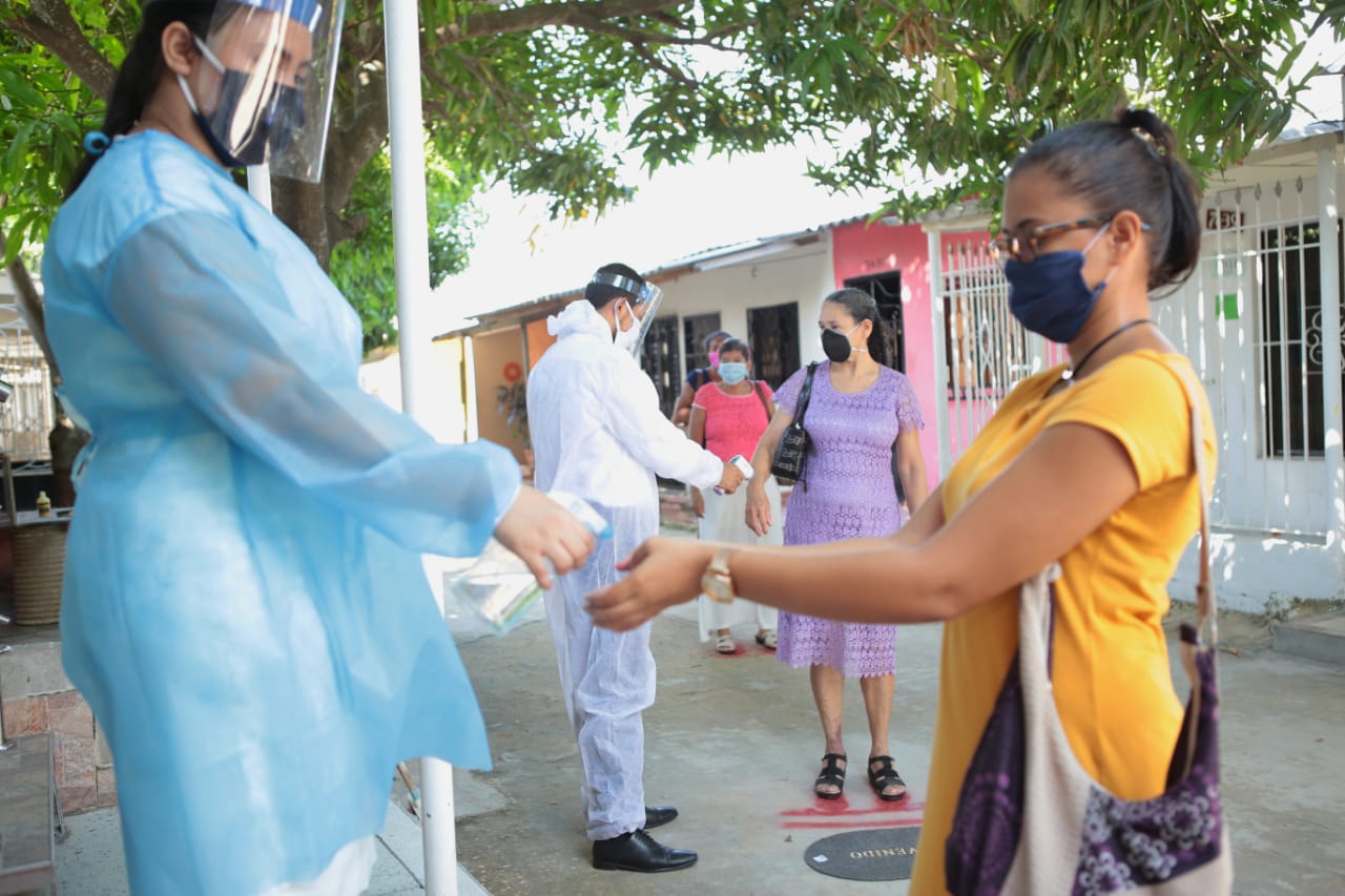 El lavado de manos con alcohol y toma de temperatura antes de ingresar a la iglesia.