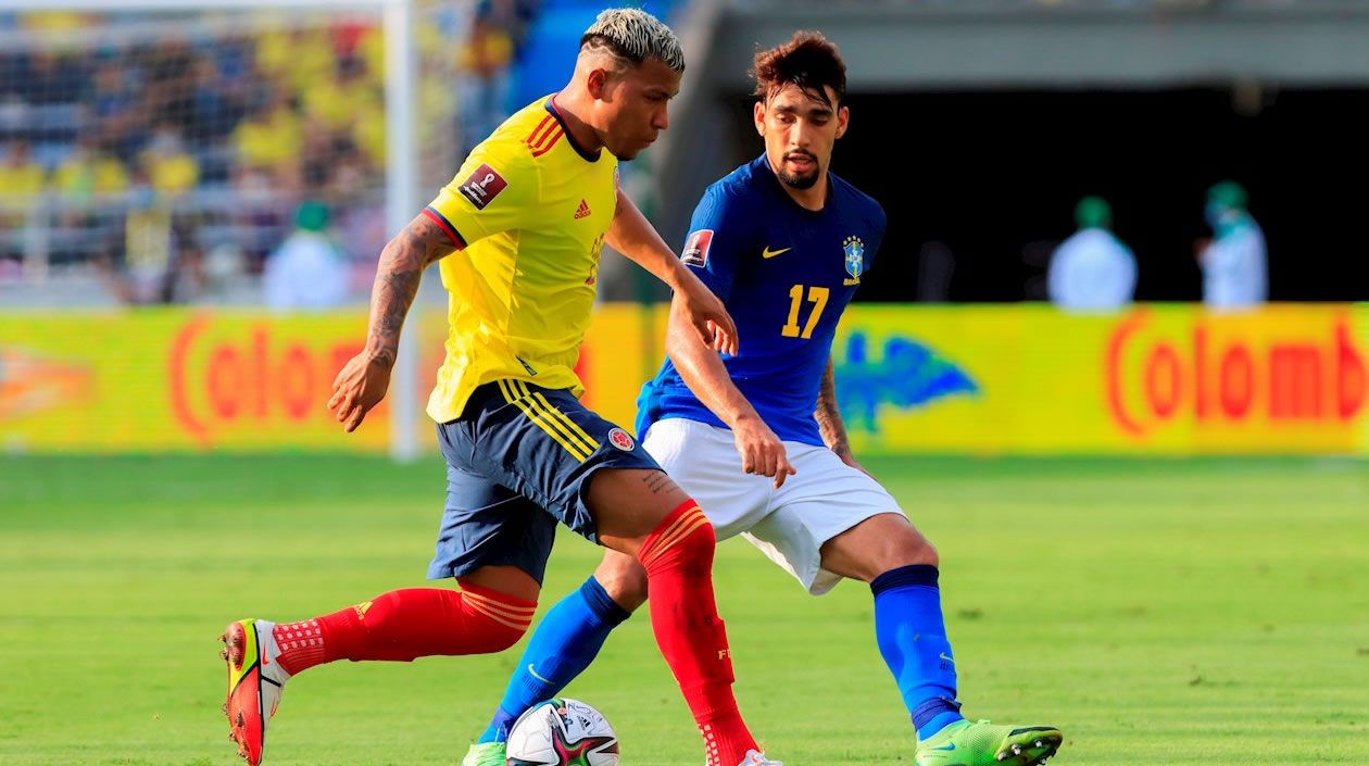 Roger Martínez de Colombia disputa un balón con Lucas Paquetá