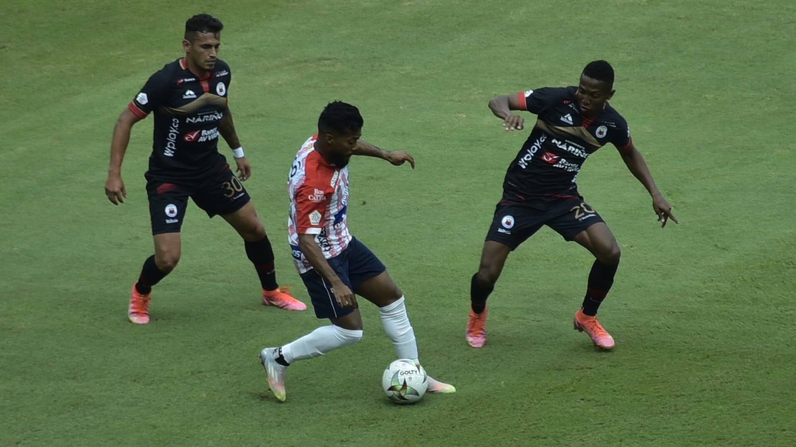 Luis 'Cariaco' González tratando de eludir a César Quintero y Esneyder Meza.