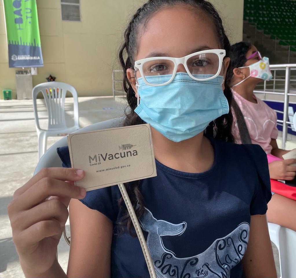 Una niña muestra su carnet de vacunación, tras aplicarse una dosis contra el Covid-19.