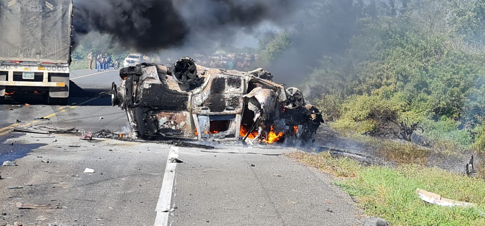 El vehículo transportador de valores volcado e incendiado. 