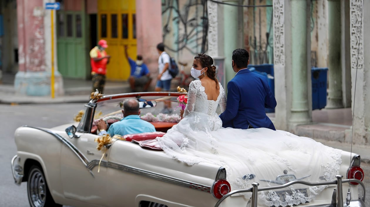 Una pareja de novios paseándose en un carro descapotado.