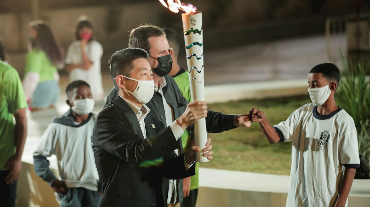 El Alcalde de Río de Janeiro, Eduardo Paes (c), saluda al niño Alexandre Custodio mientras camina junto al cónsul general de Japón.