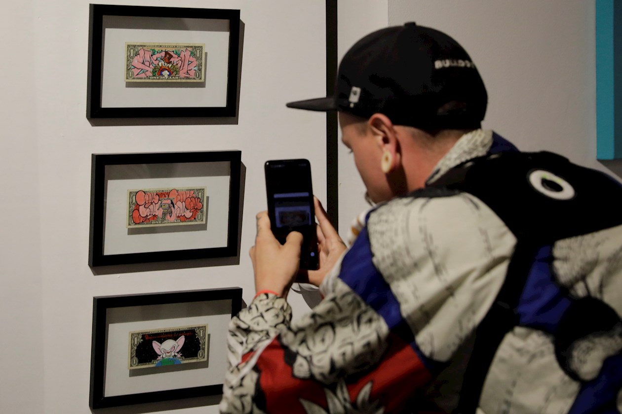 Un hombre toma fotos en la exposición de grafiti "Más que Calle",  en Bogotá.