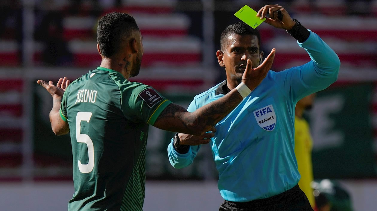 El árbitro venezolano Alexis Herrera amonesta a Adrián Jusino de Bolivia.