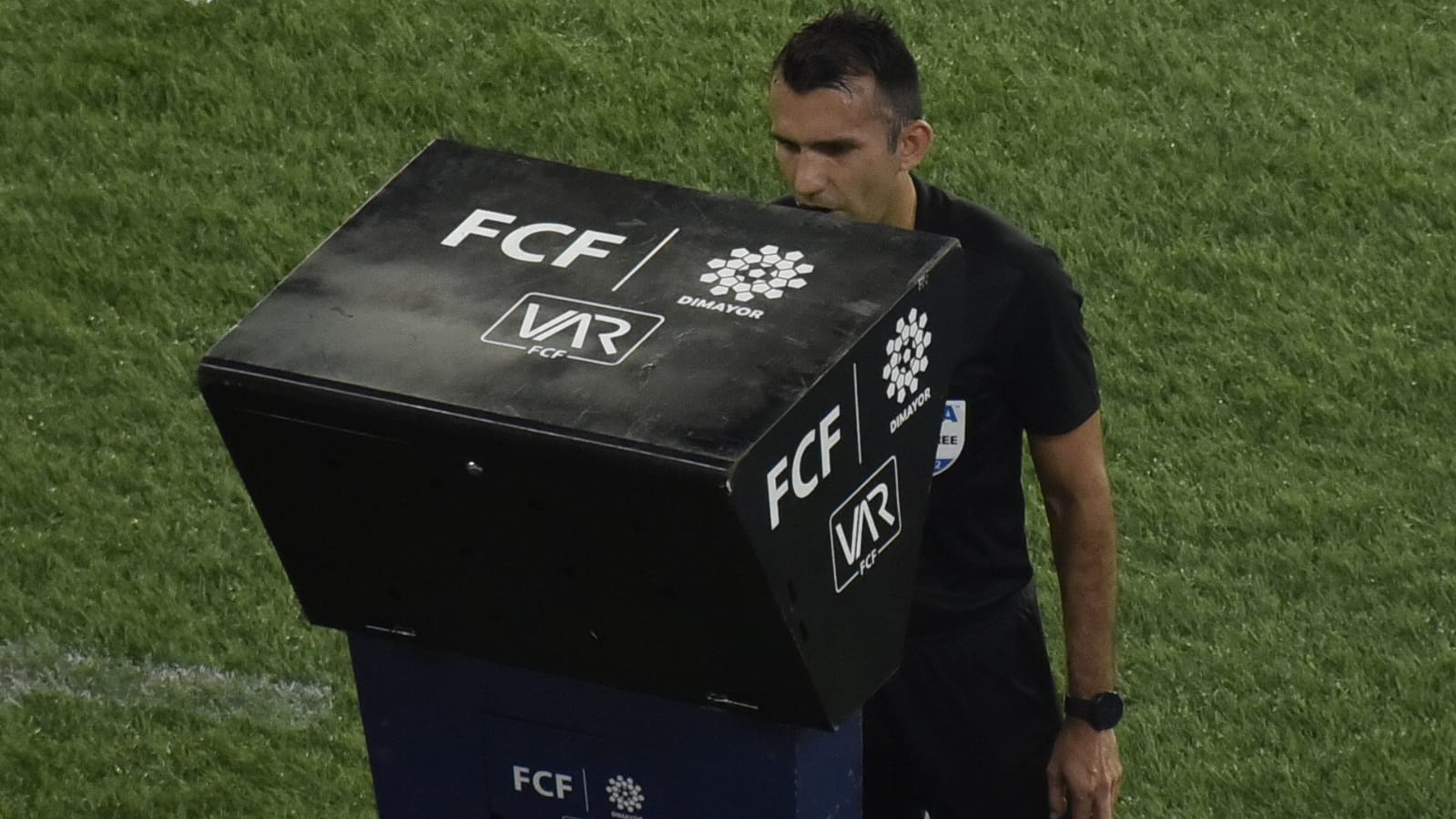 El árbitro Carlos Betancur revisando el VAR,