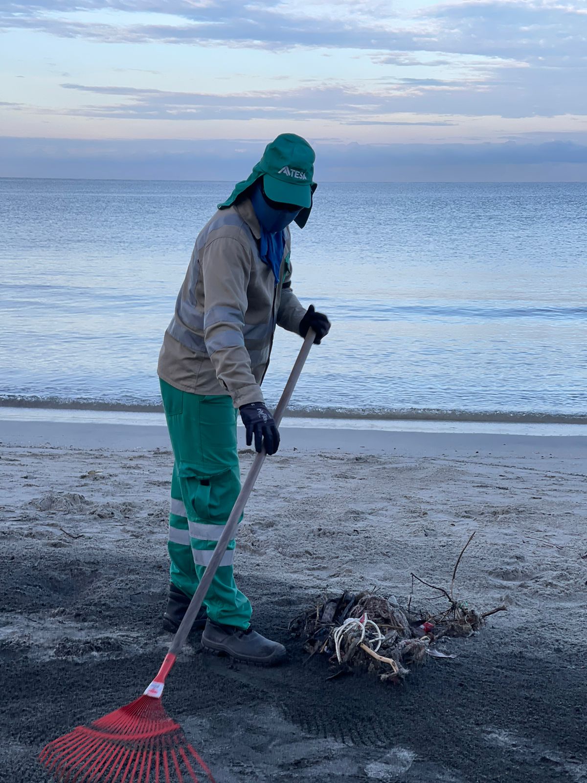 Colaborador de Atesa limpiando la zona de una playa. 