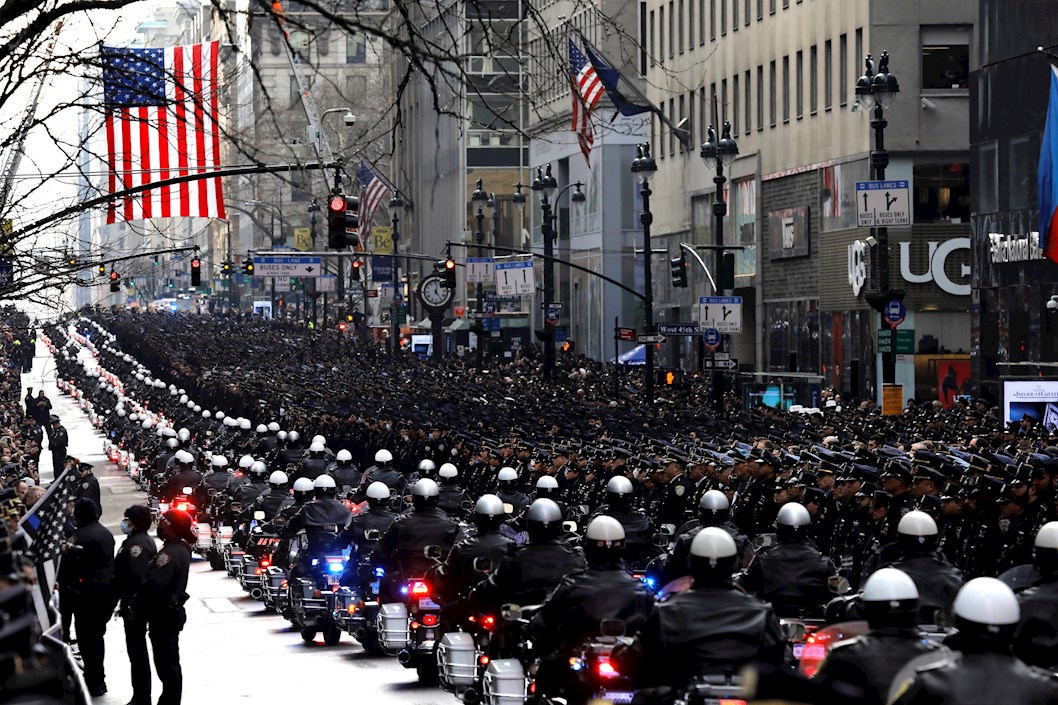Oficiales de policías reunidos en la Quinta Avenida saludan a la procesión fúnebre del oficial de policía asesinado de la ciudad de Nueva York, Wilbert Mora, afuera de la Catedral de San Patricio en Nueva York.