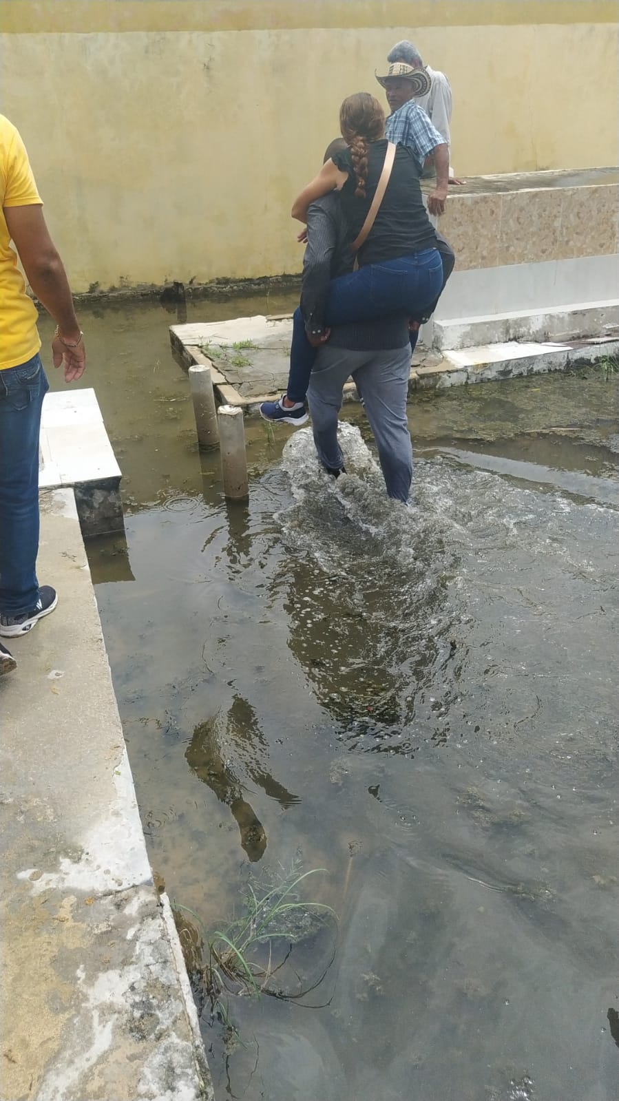 Habitantes cruzando el charco de agua en el cementerio. 