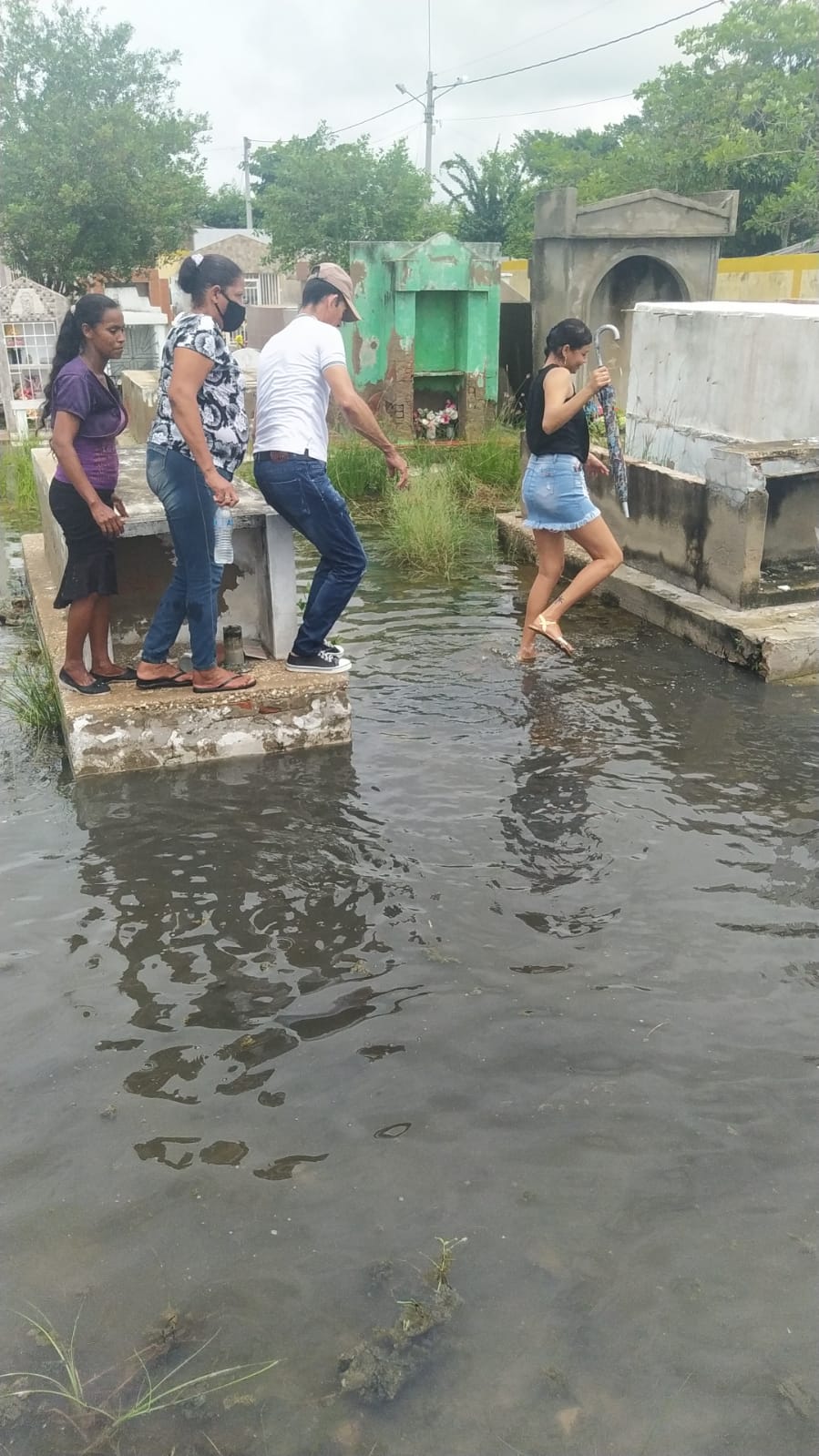 Habitantes cruzando el charco de agua en el cementerio. 