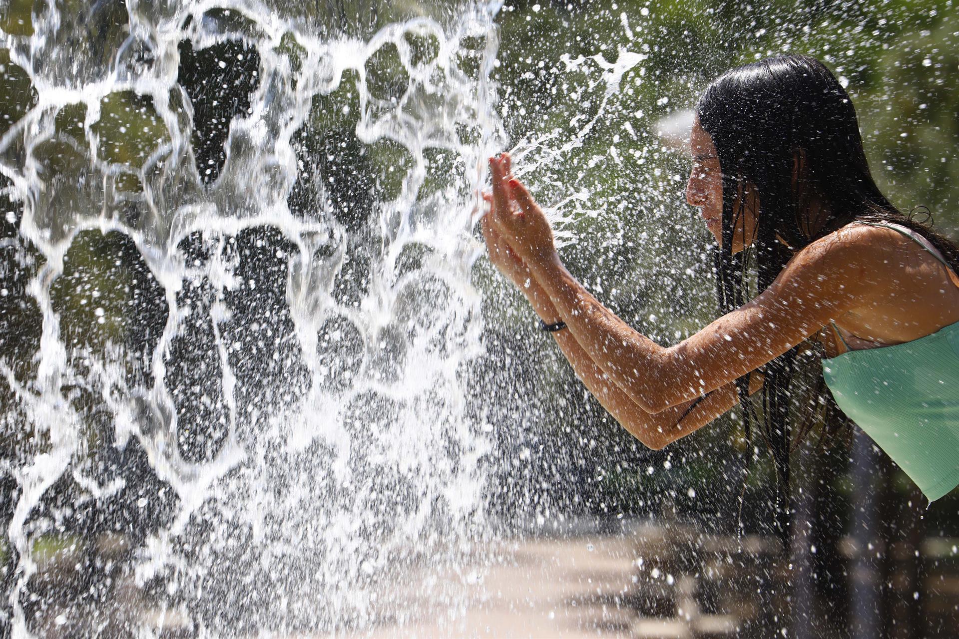 Una mujer se refresca en una de las fuentes del centro de Córdoba (España) este domingo.