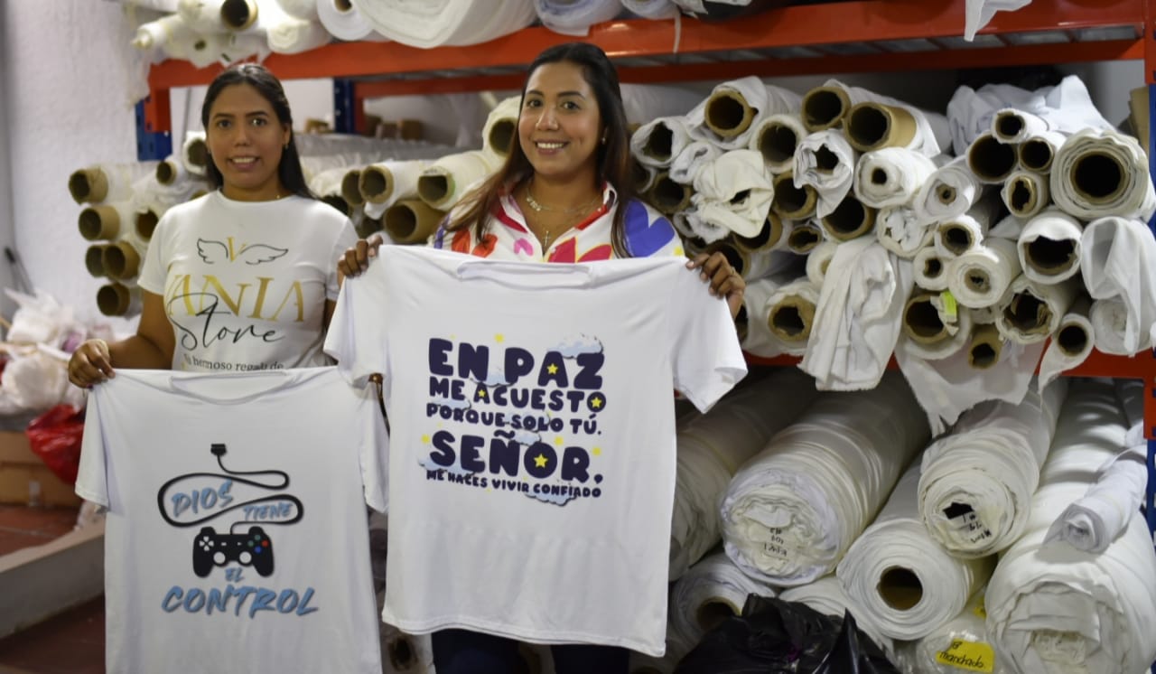 Kelly junto a su hermana Gilma enseñan algunas de las camisetas de su emprendimiento.